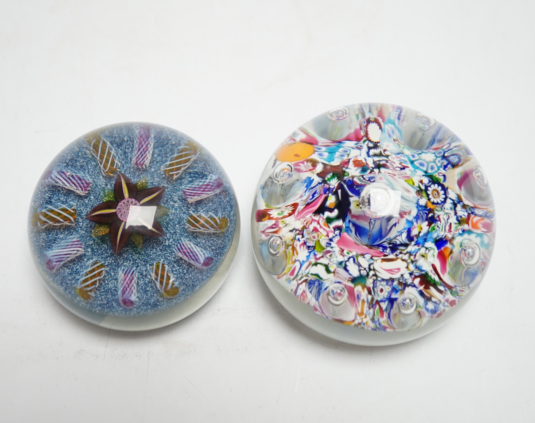 Two Paul Ysart glass paperweights, comprising a purple flower and latticino spoke on a blue jasper ground, ‘H’ cane, PY label, 7cm and ‘Harlequin’ glass paperweight, PY paper label, 8cm